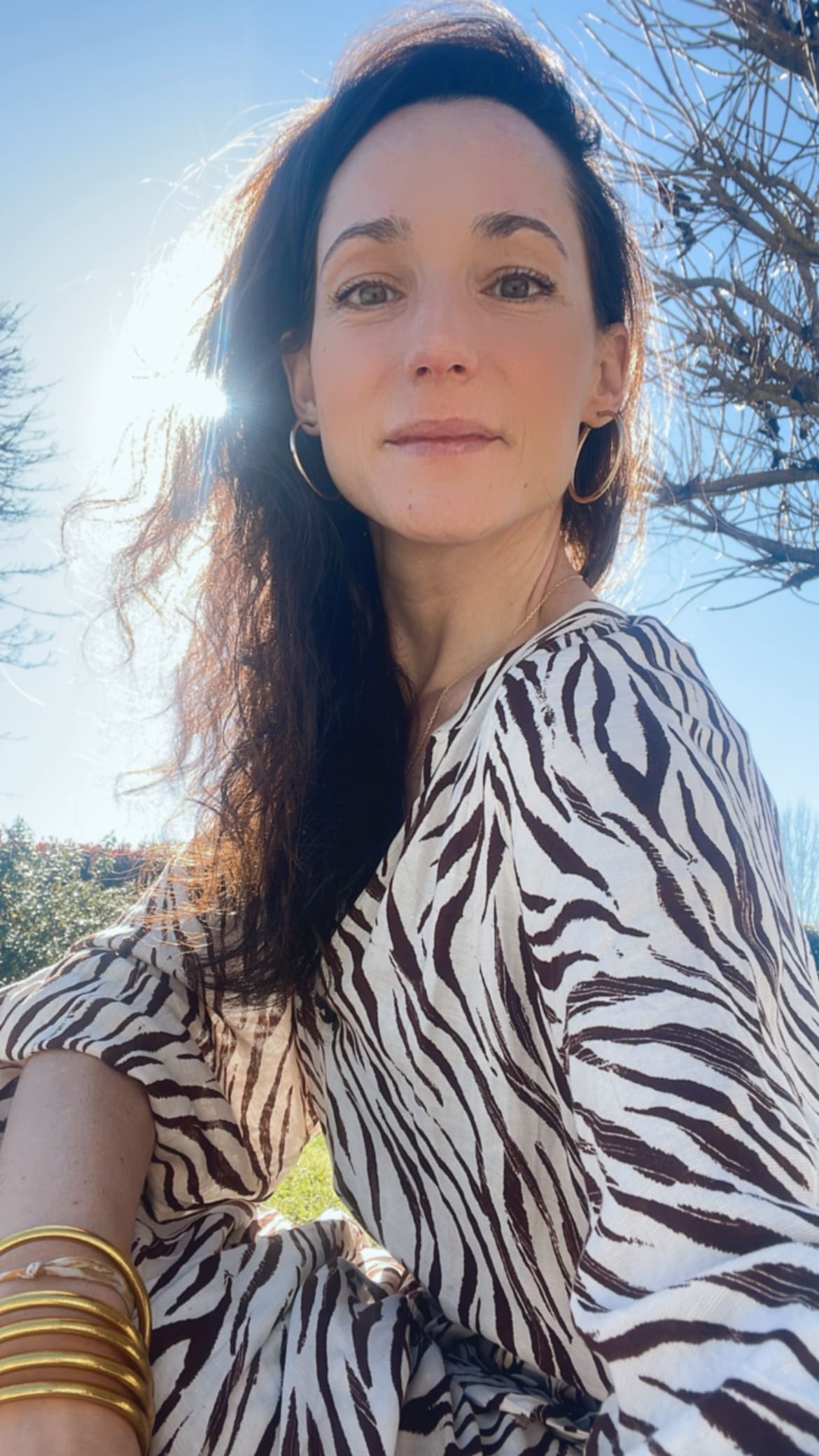 portrait d'élodie votre photographe souriante avec soleil derrière moi et le ciel bleu 